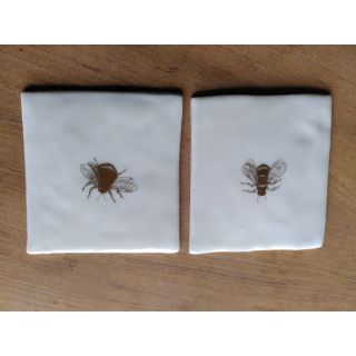 Two porcelain tiles/coasters with a gold bee